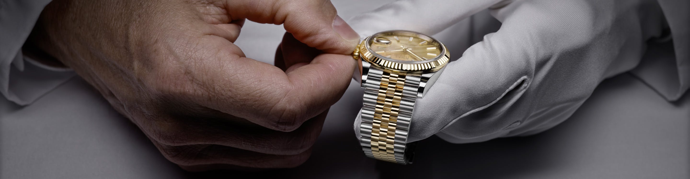 Photo of two hands holding a Rolex watch