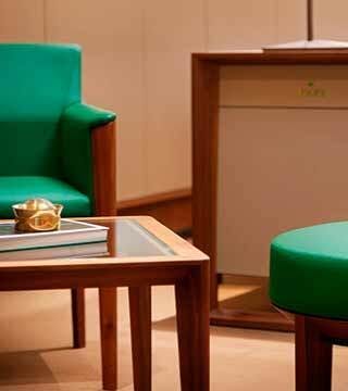 Signature Rolex green chair seated at a table in a Rolex Showroom at Lee Michaels Fine Jewelry.
