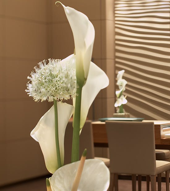 Beautiful white flowers sit forefront of an image of the Rolex showroom.